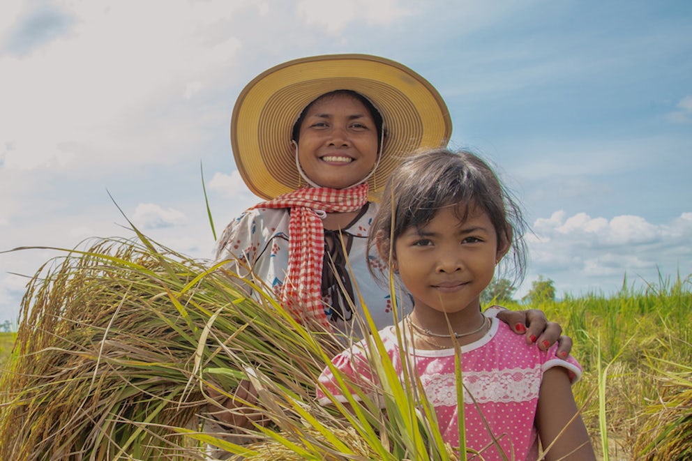 mother and daughter standing in a field holding their harvest