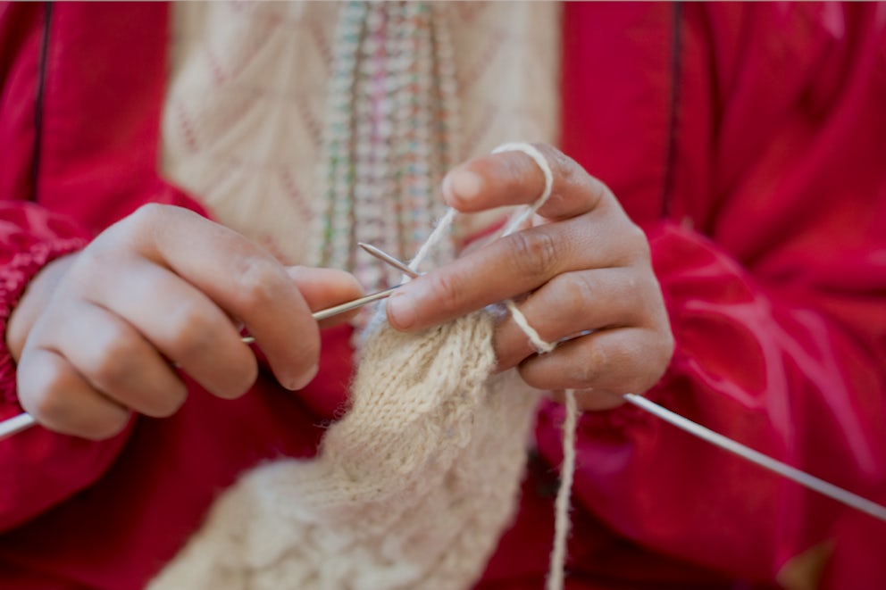 A close up photo of a woman's hands knitting.