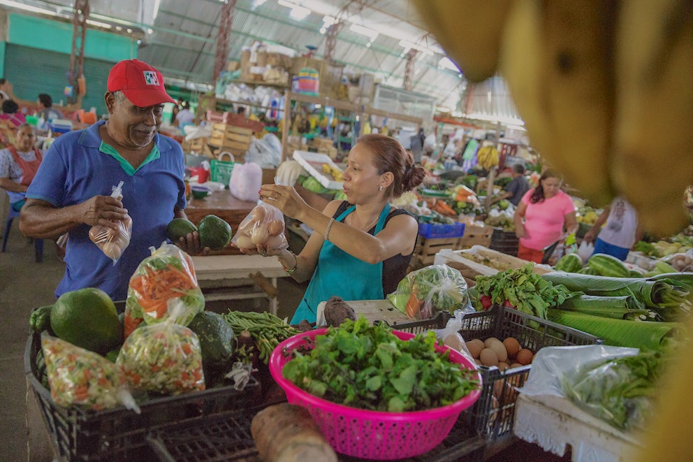 Woman selling eggs to a man in a Mexican market.