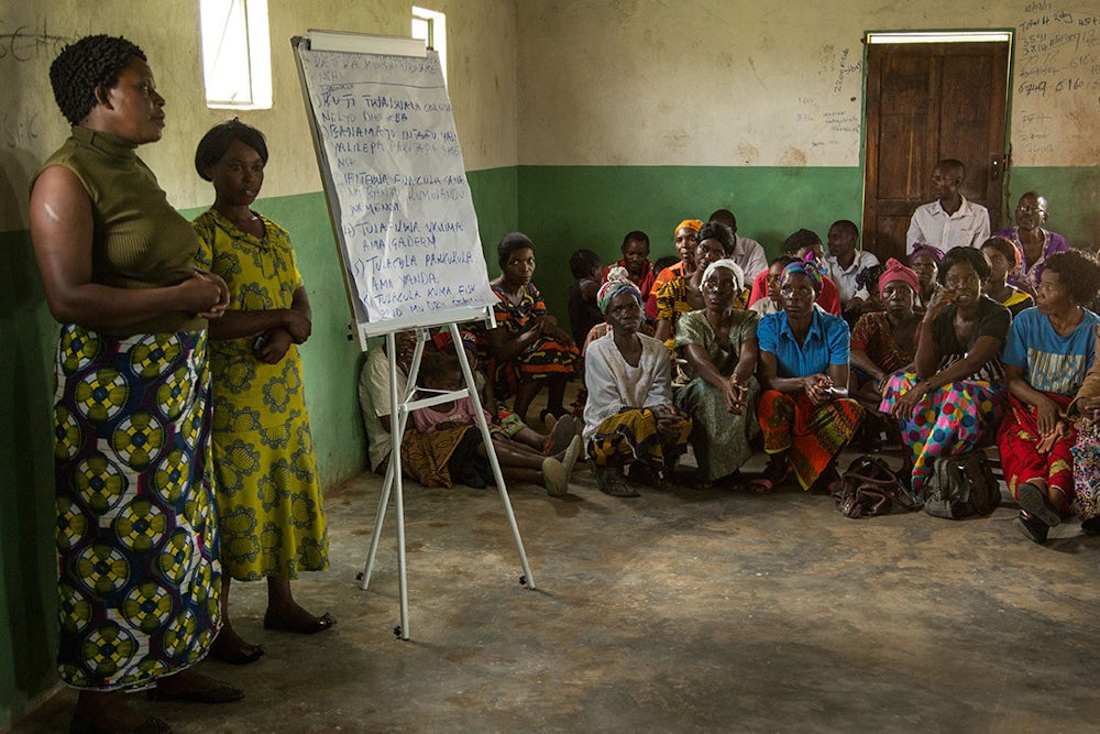 Two women in a building in Zambia present to a group of adults.