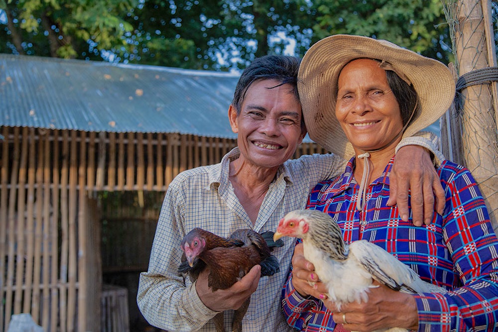 Man and woman holding chickens and smiling.