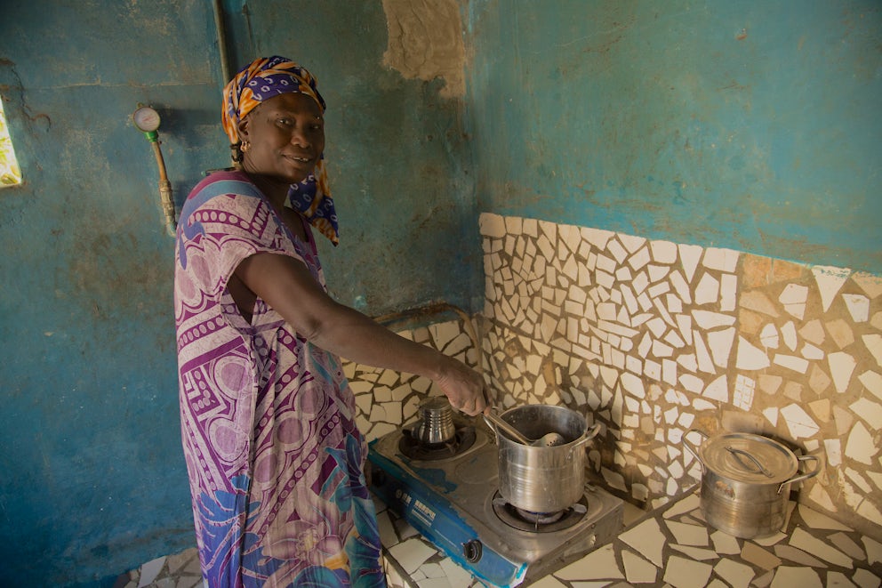 A woman in colorful clothing stirs a pot.