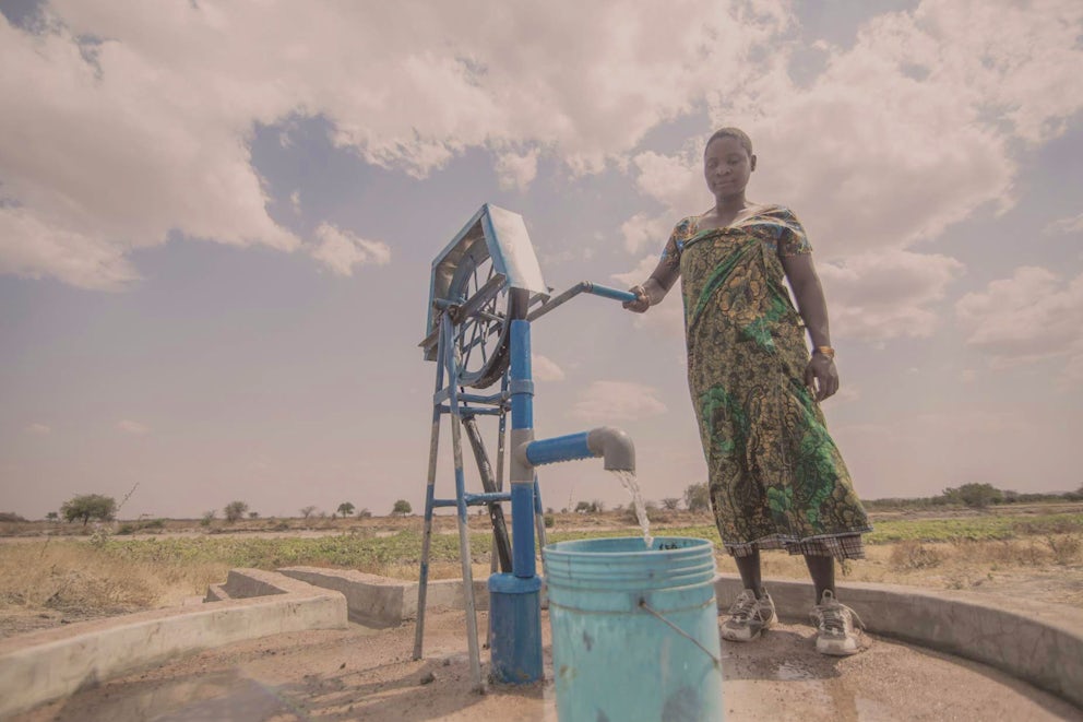 Woman filling a bucket with water from a well