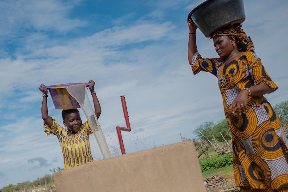 Woman with a child retrieving water from a well.