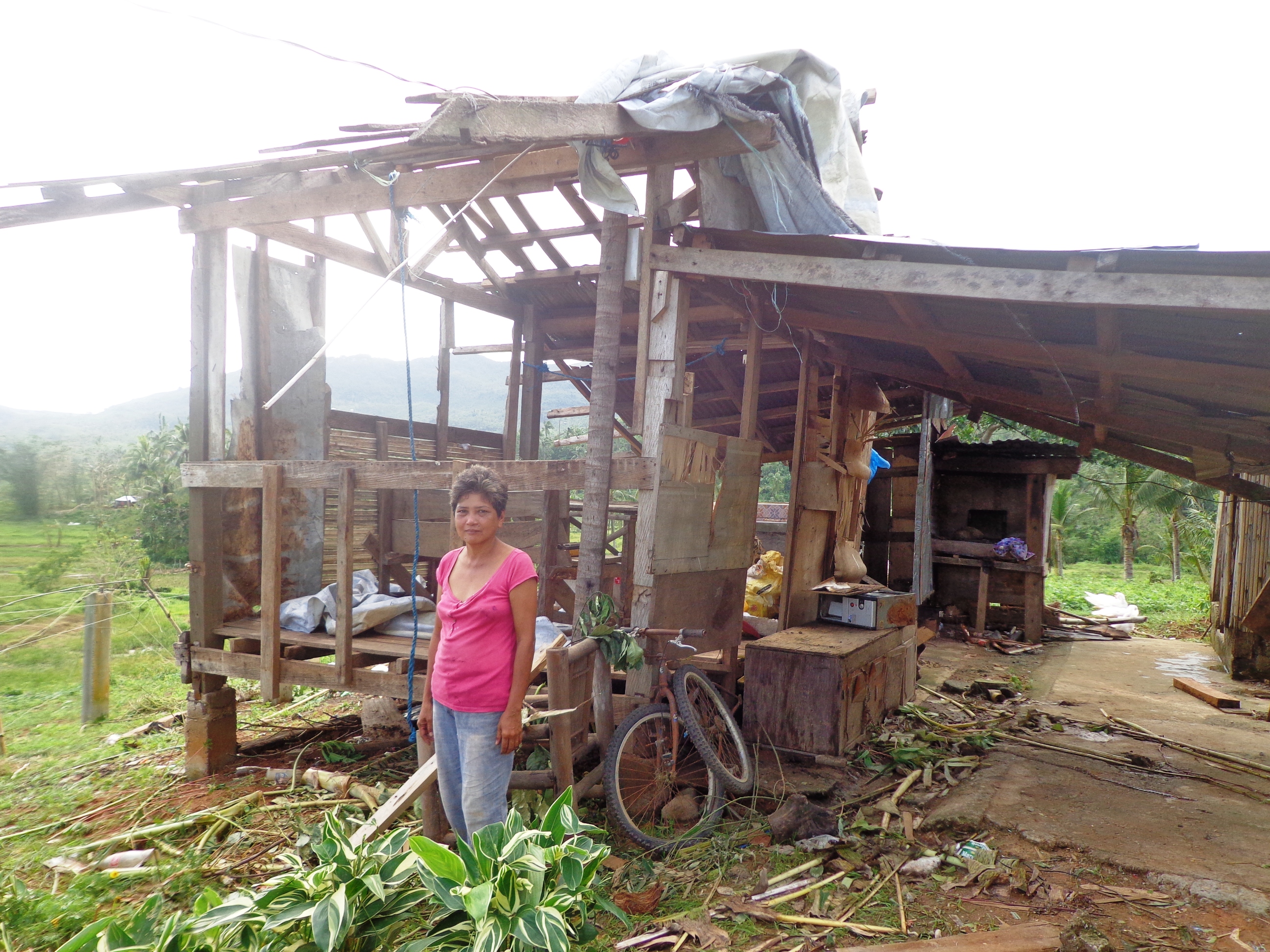 Heifer International Philippines project participant surveys her damaged home