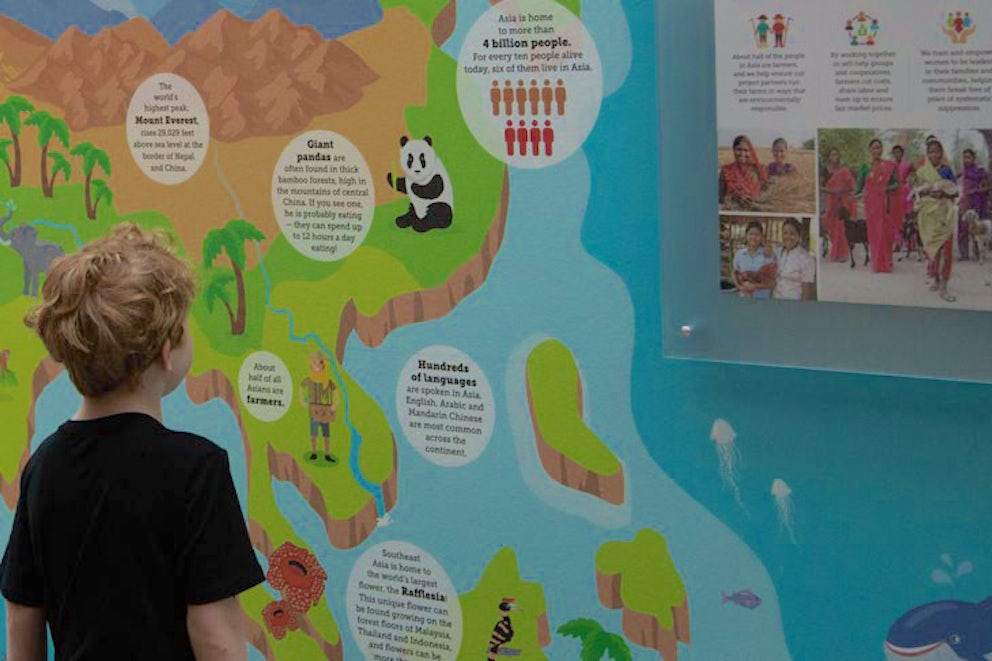 A preschooler in front of an illustrated wall at Heifer Village.