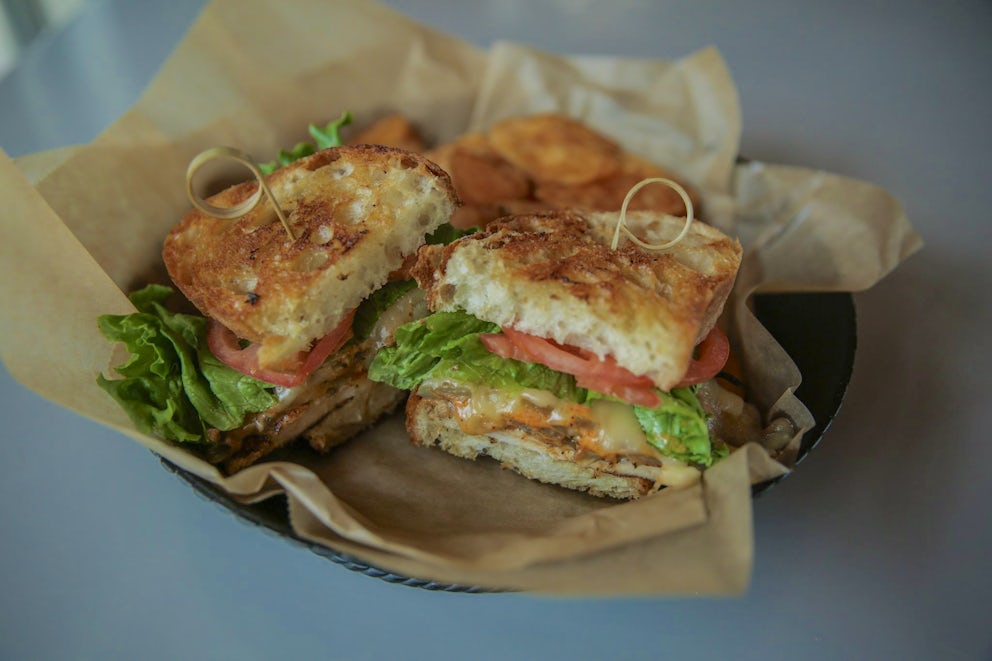 A cheesy sandwich with lettuce and tomato on crusty bread.