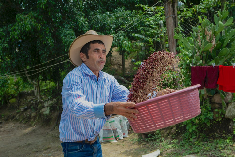 A man flips a bowl of beans into the air.