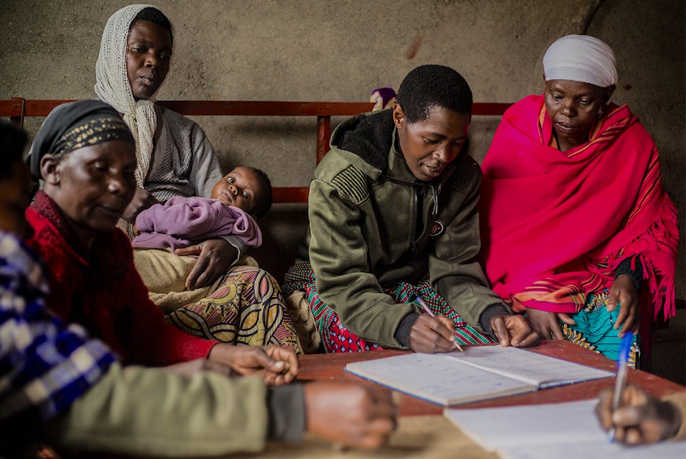A group of women sit together and consult paperwork in Rwanda.