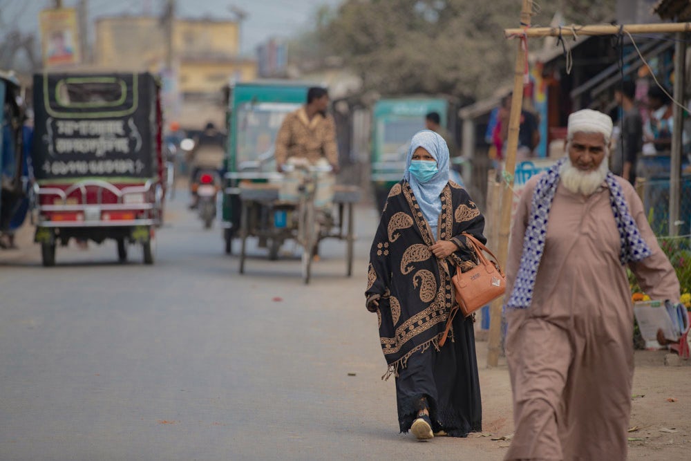 A woman walks toward the camera on a busy street in Bangladesh.