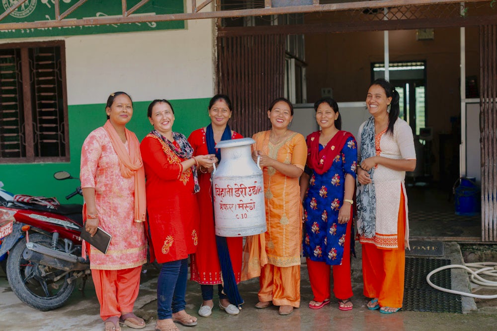 A group of women in Nepal holding a milk container for a group photo.