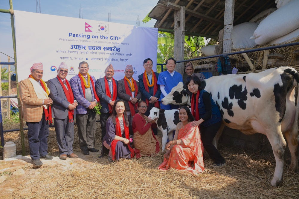 A group of individuals in traditional and business attire pose for a photo at an agricultural event.
