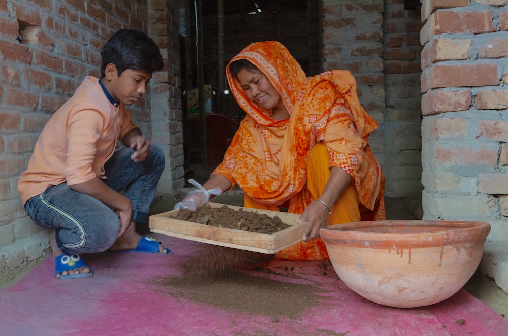 A Bangladeshi woman and her son tend to a basket of compost.