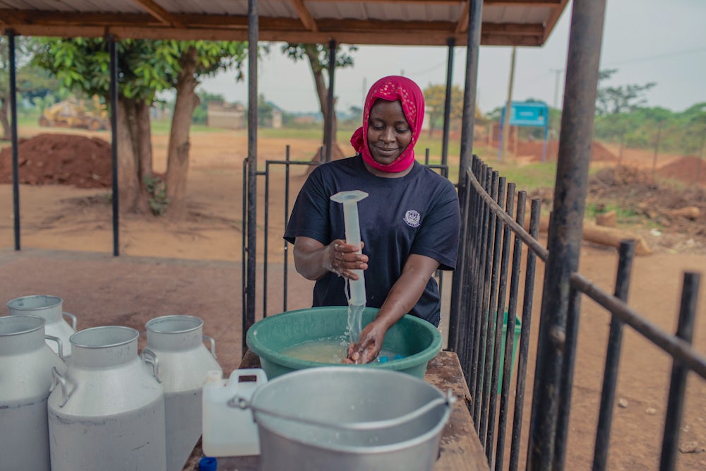 A Ugandan woman cleans milk processing equipment.
