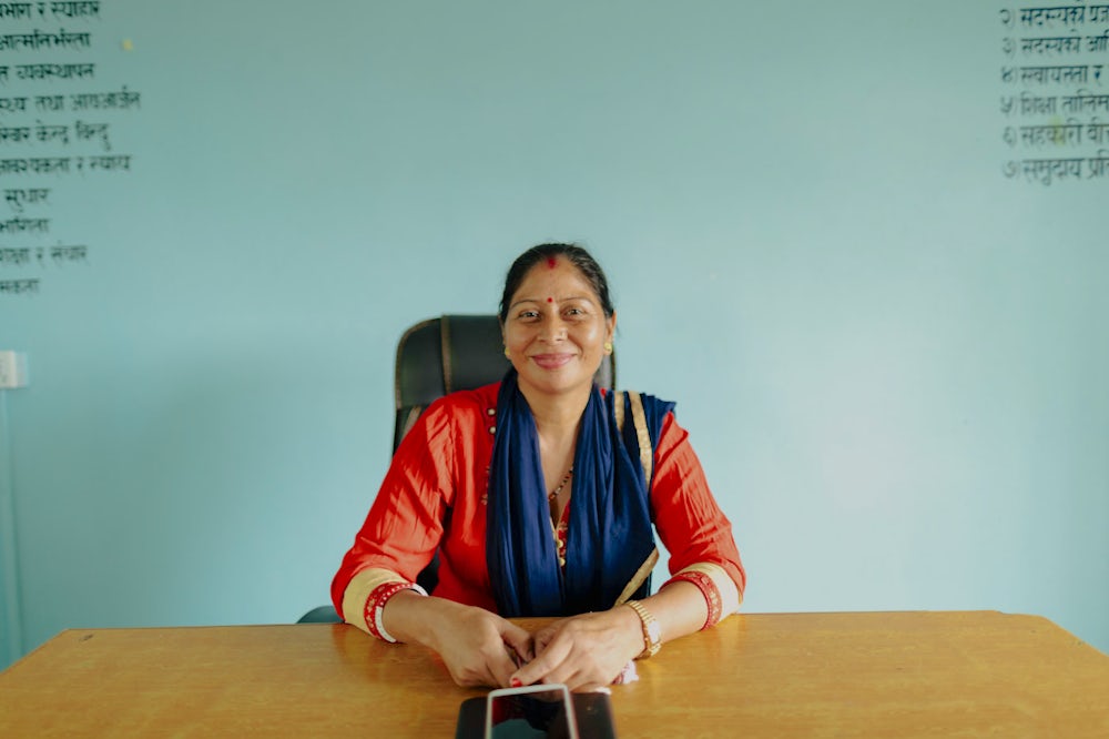 A woman sits at her desk for a portrait in Nepal.