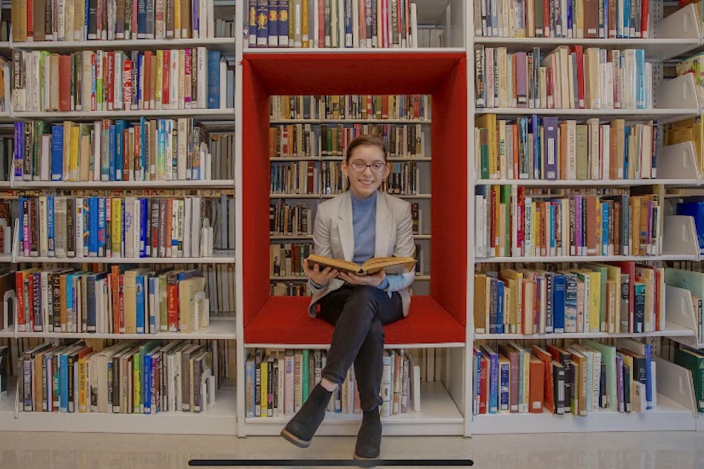 A portrait of a girl sitting in a library.