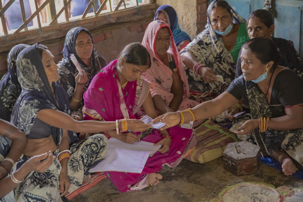 A group of women collecting money as savings for their self help group.