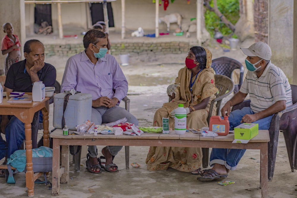 Kunti Devi sitting with a group of men and participating in a discussion around challenges to animal health in the area. 