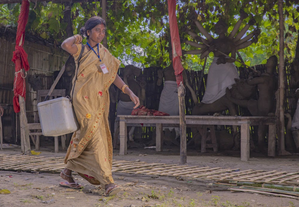 Kunti Devi, a farmer and an animal healthcare worker carrying a cold box full of vaccines and deworming medicines on her shoulder. 