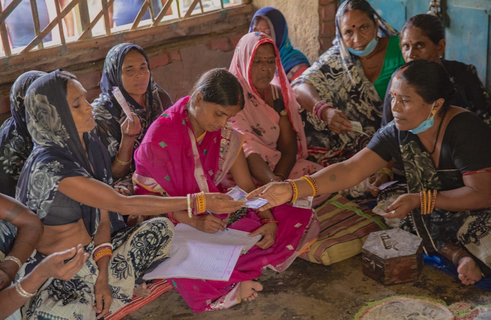 A group of women sit together in a circle in India.