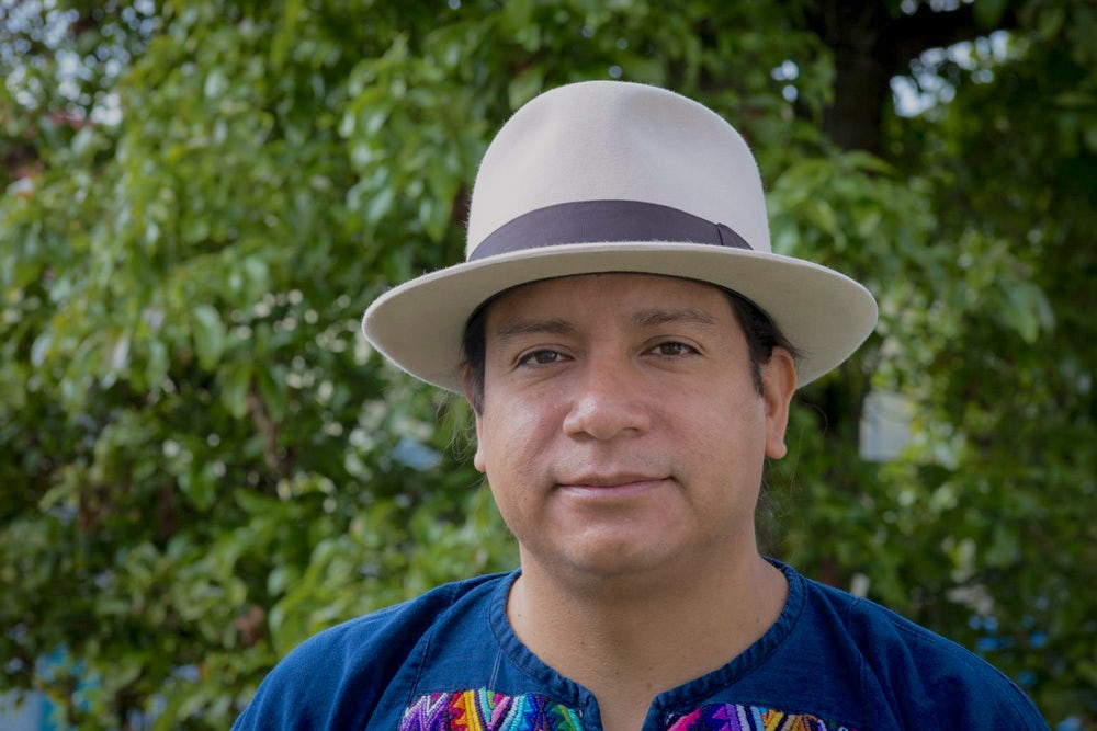 A man wearing a hat and blue shirt stares at the camera.