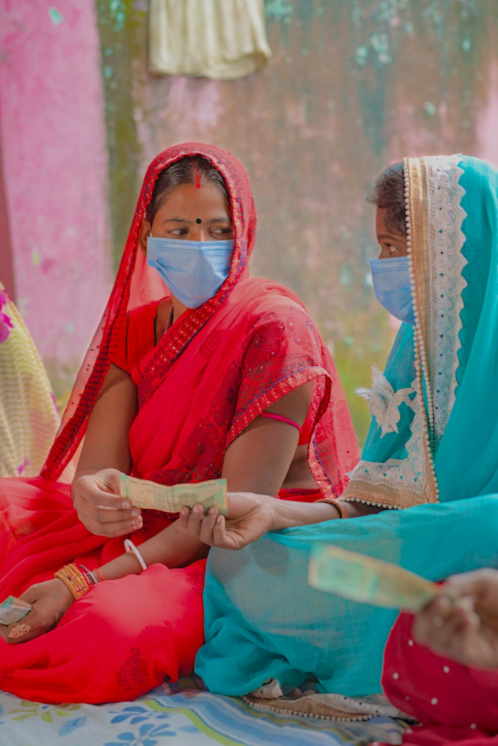 Two women in India exchange money as part of a group savings exercise.