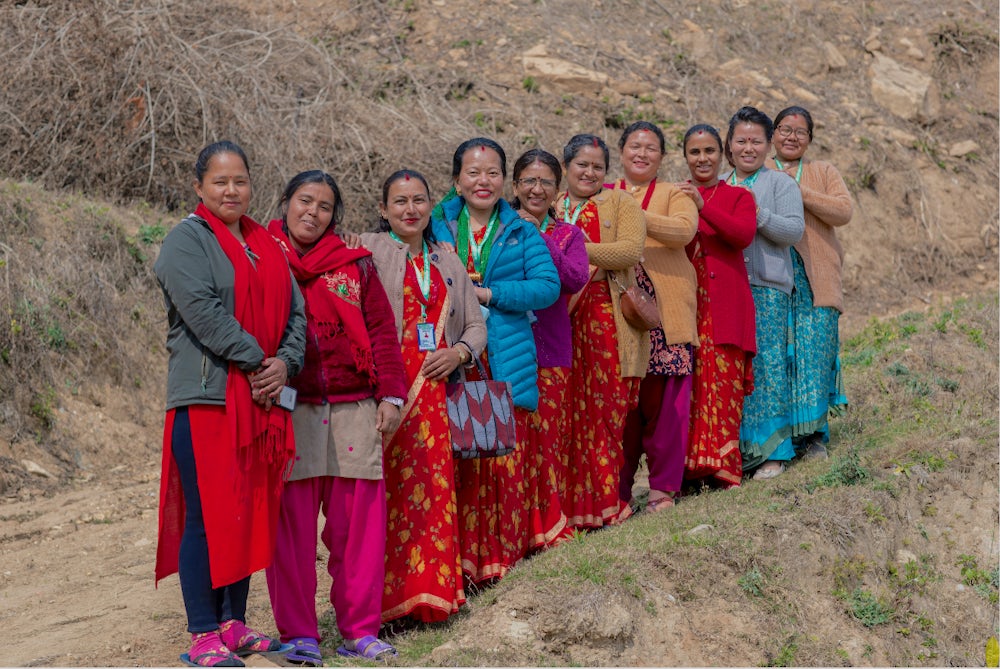 Women from a cooperative in Nepal confidently pose for a picture.