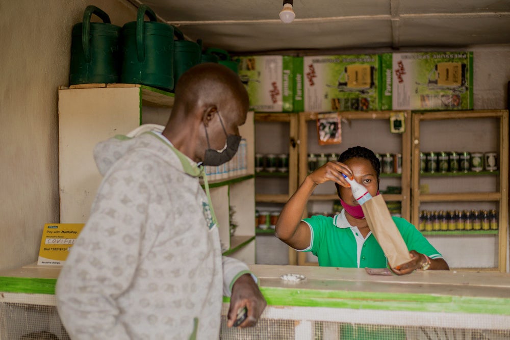 A young woman helps a farmer at a shop in Rwanda.
