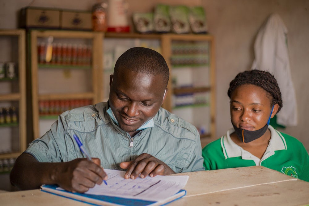 Two people conduct bookkeeping at a shop in Rwanda.