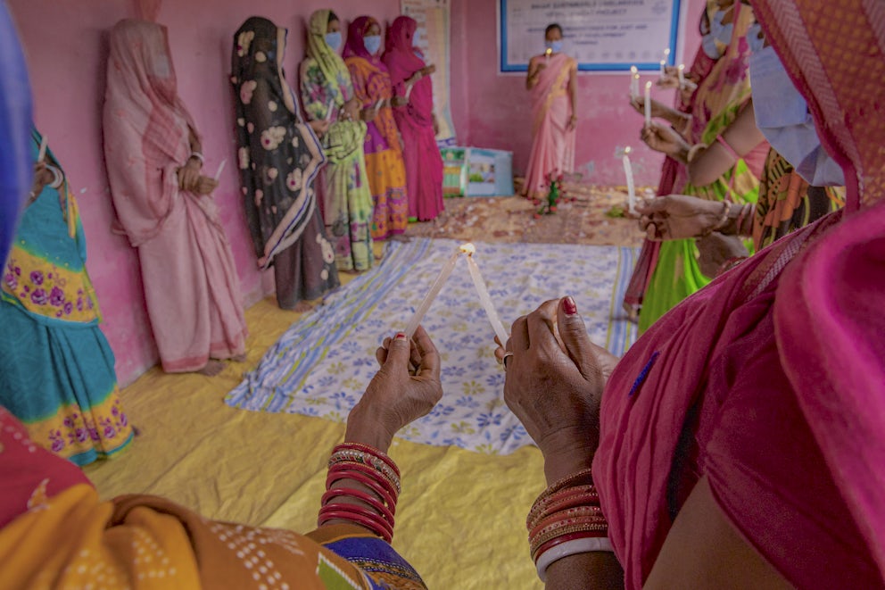 Women lighting candles and passing on the flame during a training session in a village.