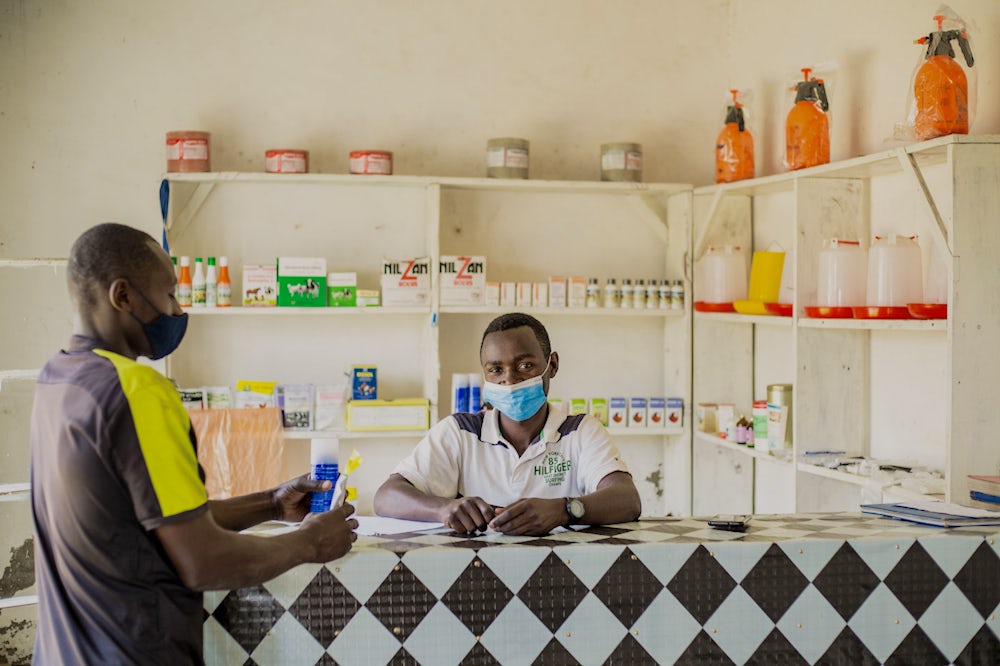 Two men stand at the counter of an agrovet shop in Rwanda.