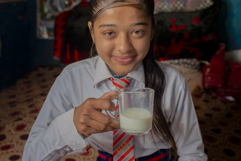 Bishnu's daughter enjoys a glass of milk.