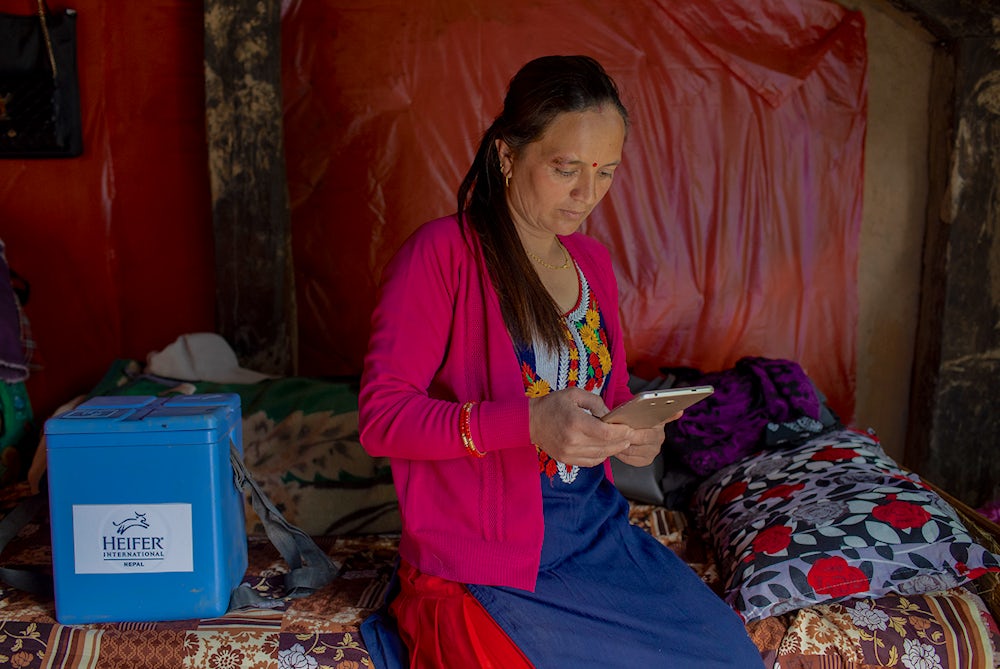 A Nepali woman checks her tablet, while sitting on a bed.