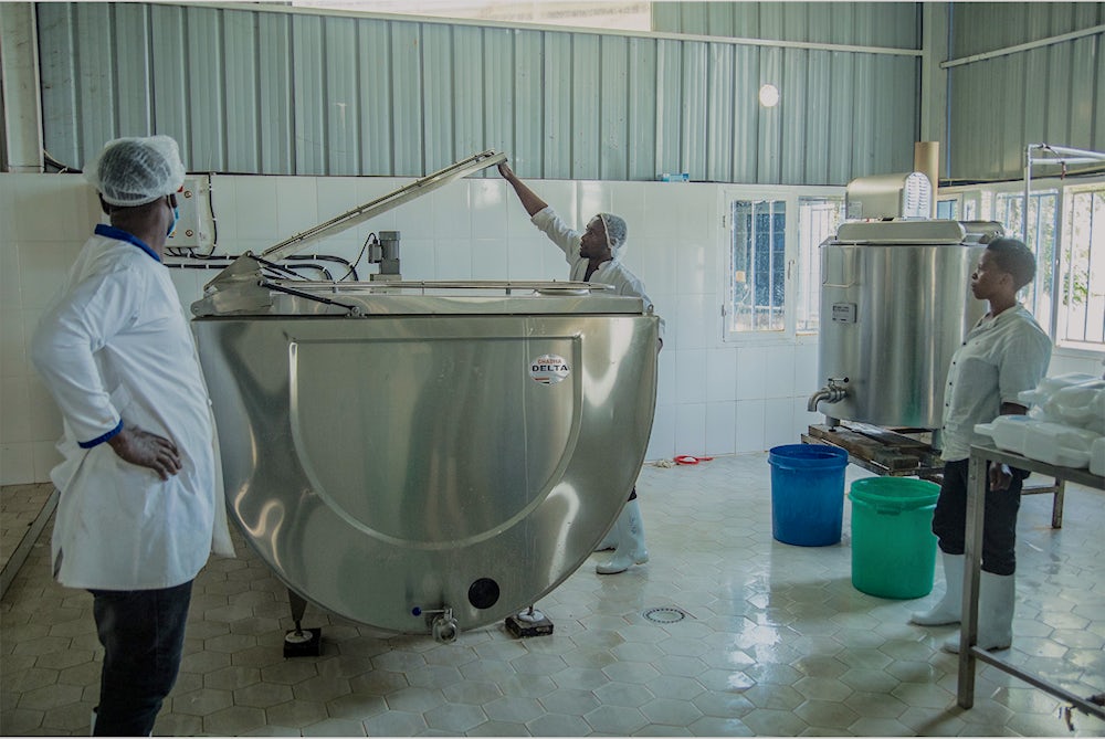 Members of a milk collection center stand around a milk chilling tank.