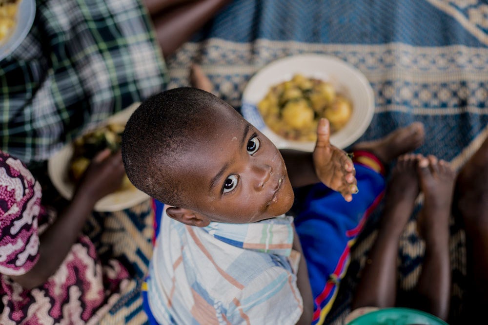 一个卢旺达男孩正在吃一盘食物。