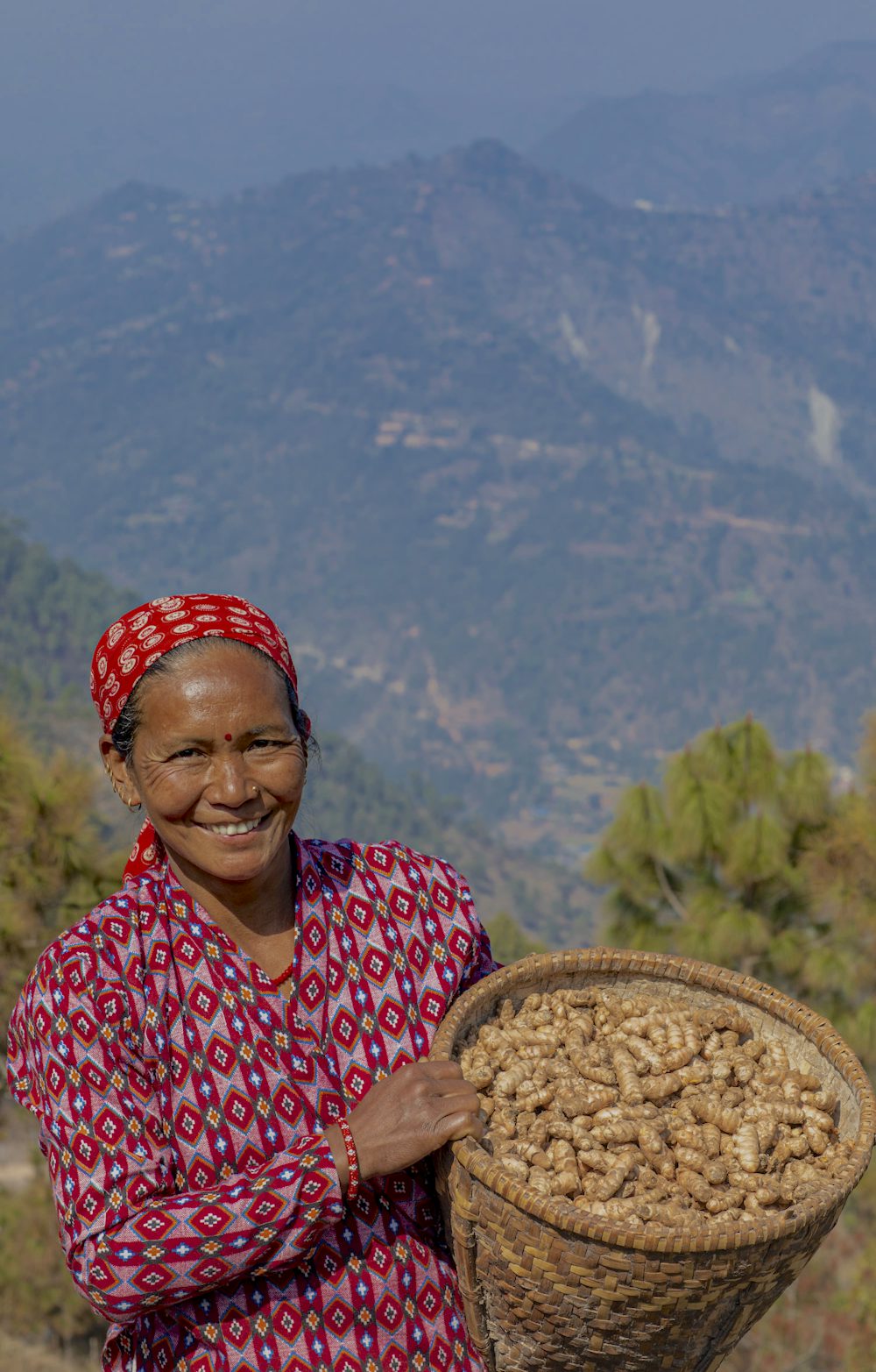 A woman smiles at the camera as she holds a basket of ginger.