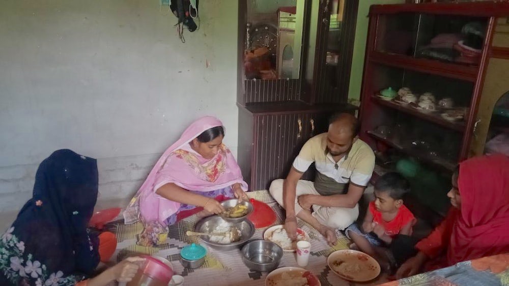A family sitting on the ground and eating food together.