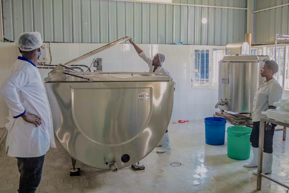 Members of a milk collection center in Rwanda tend to refrigerated tanks.