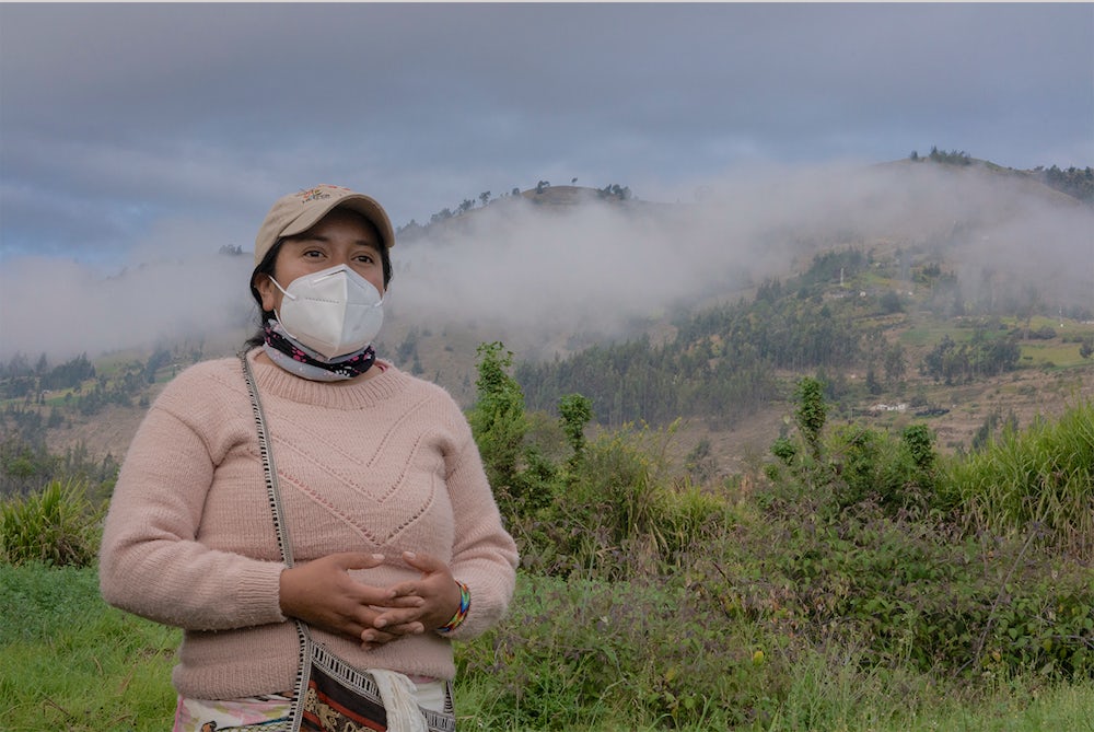 A woman wearing a face mask stands in a field.