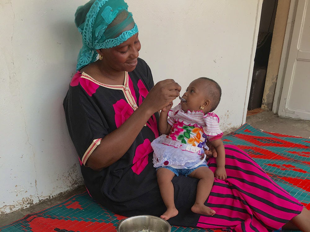 A woman feeds her baby porridge from a bowl.