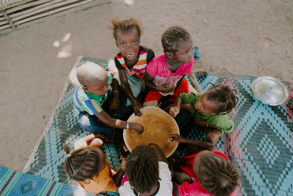 孩子们围坐成一圈，从碗里吃着营养丰富的食物。