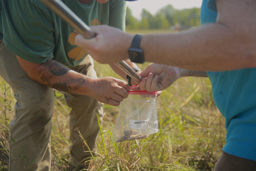 A soil sample is poured into a plastic bag.