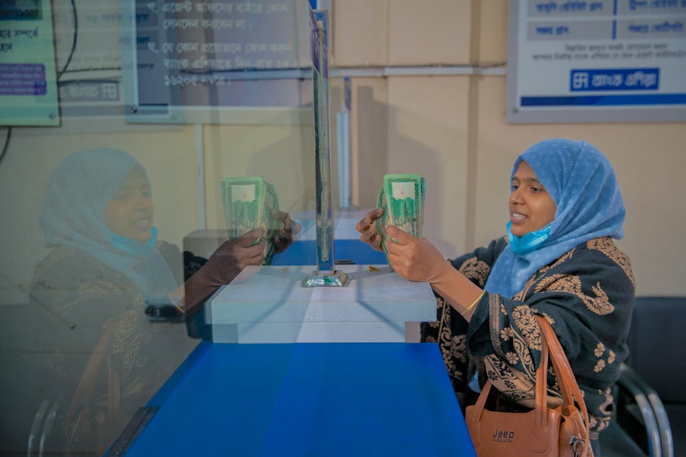 A woman at a bank counter happily exchanges money.