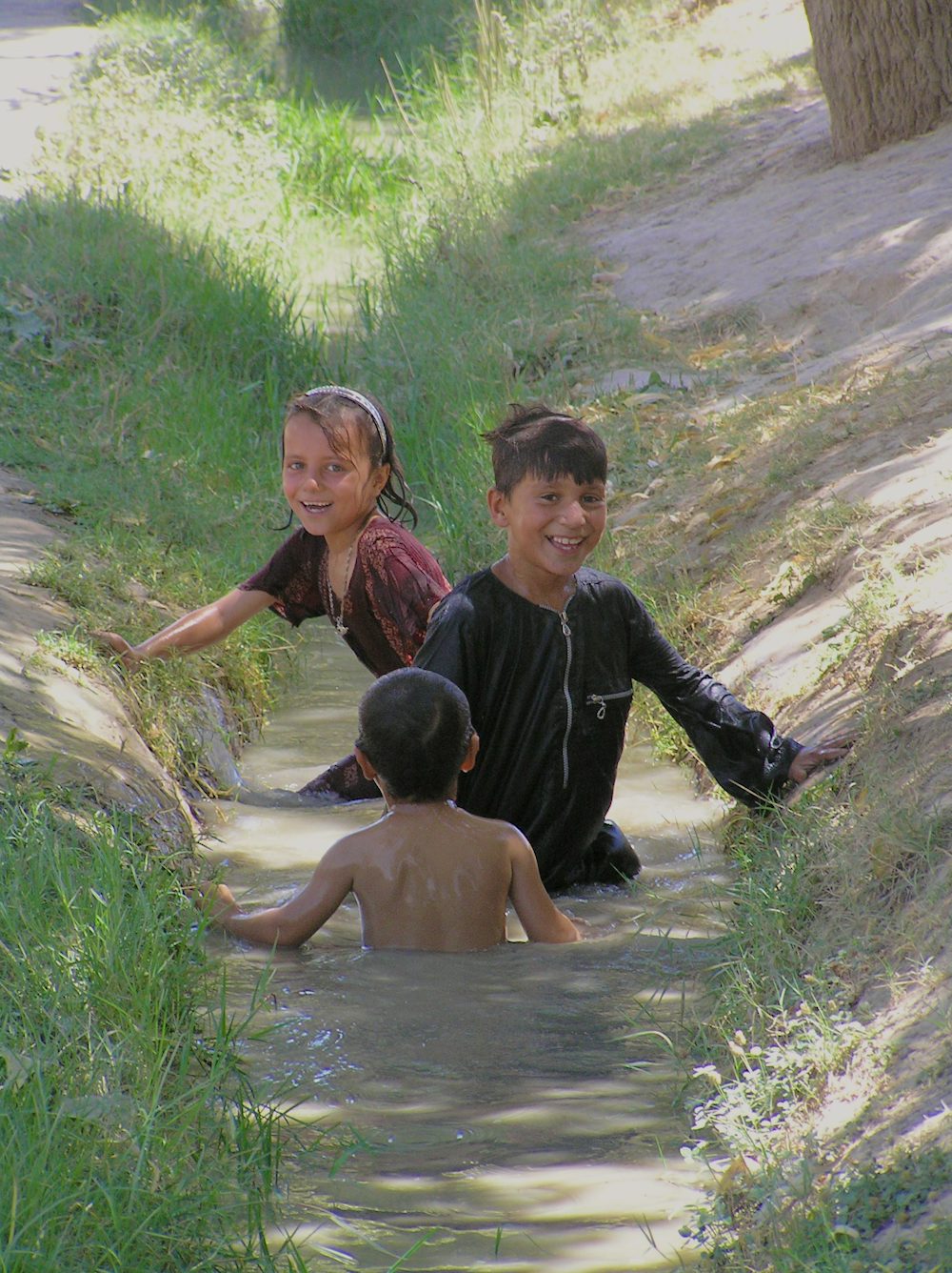 Children frolic and cool off in an irrigation canal on a blistering hot day in Balkh Province in a village outside of Mazar e Sharif.