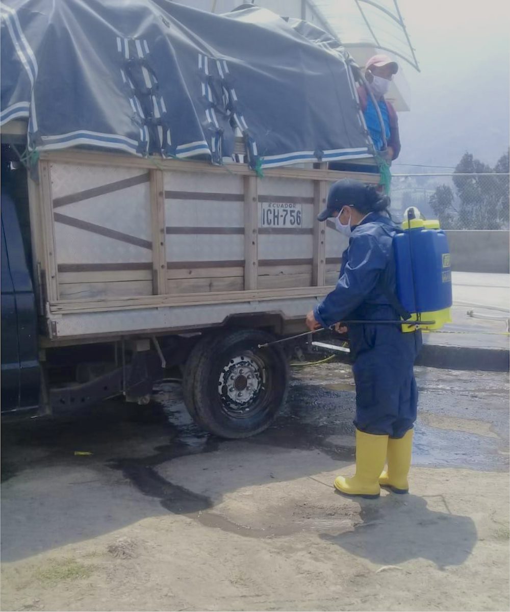 A staff member sprays a dairy truck with disinfectant.