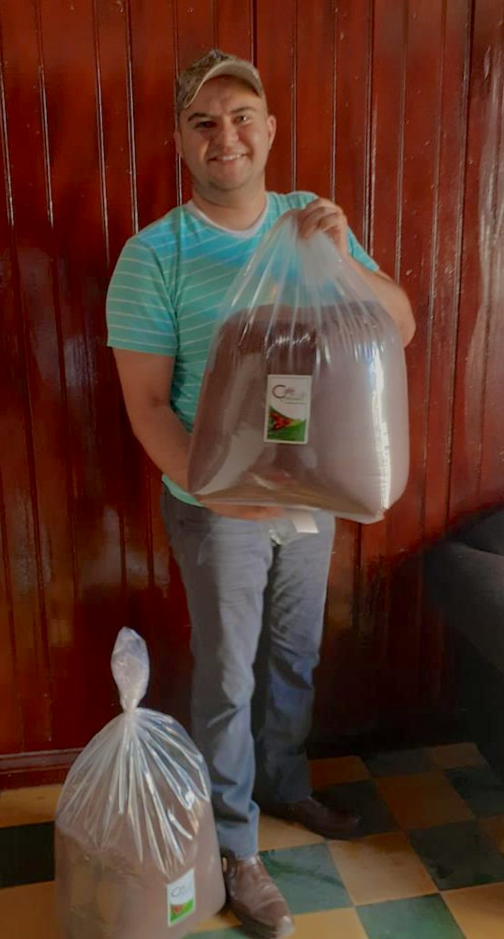 A man poses with a clear bag full of individual sachets of coffee.