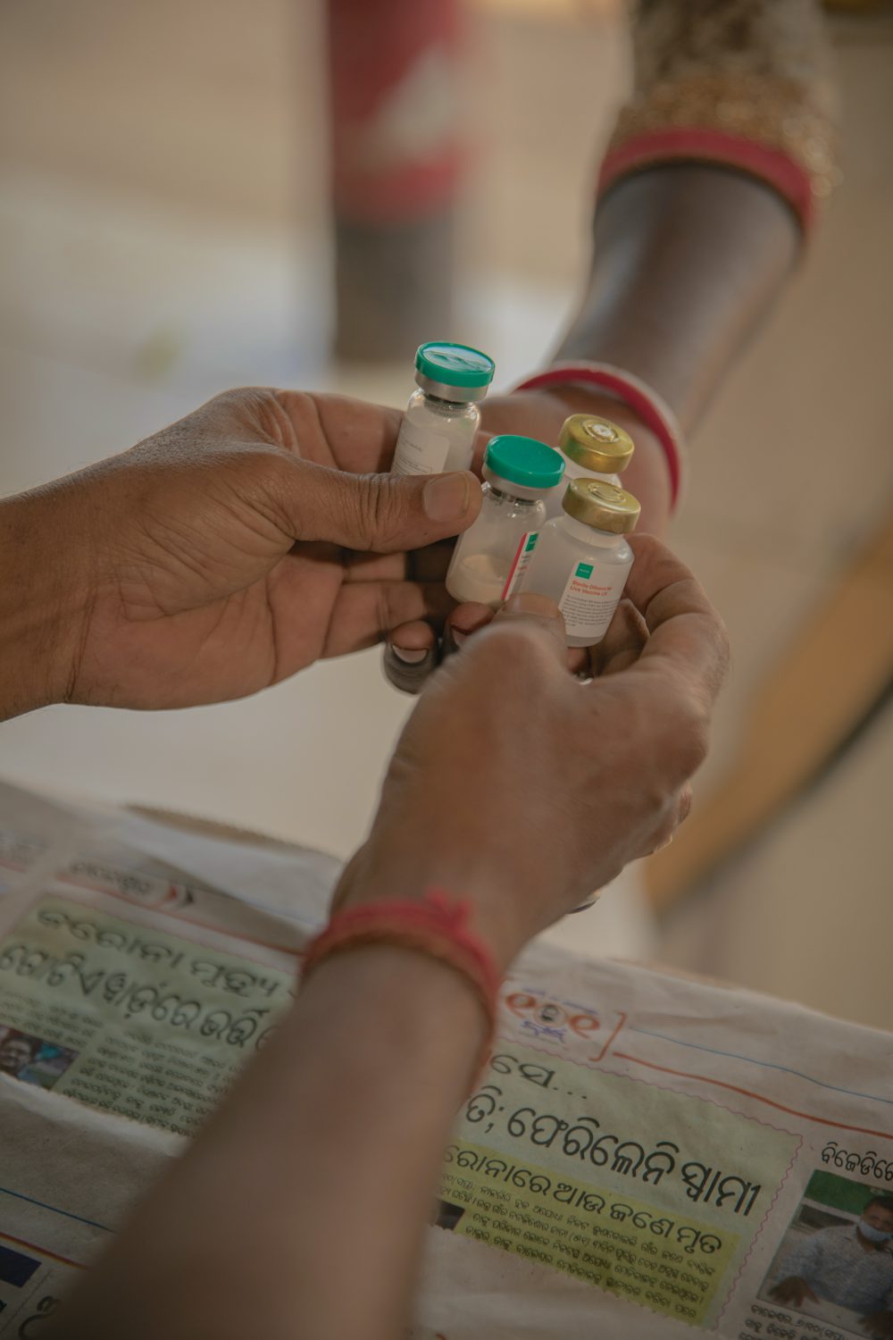 Vials of animal vaccines are handed to a vet's hand over a counter in India.