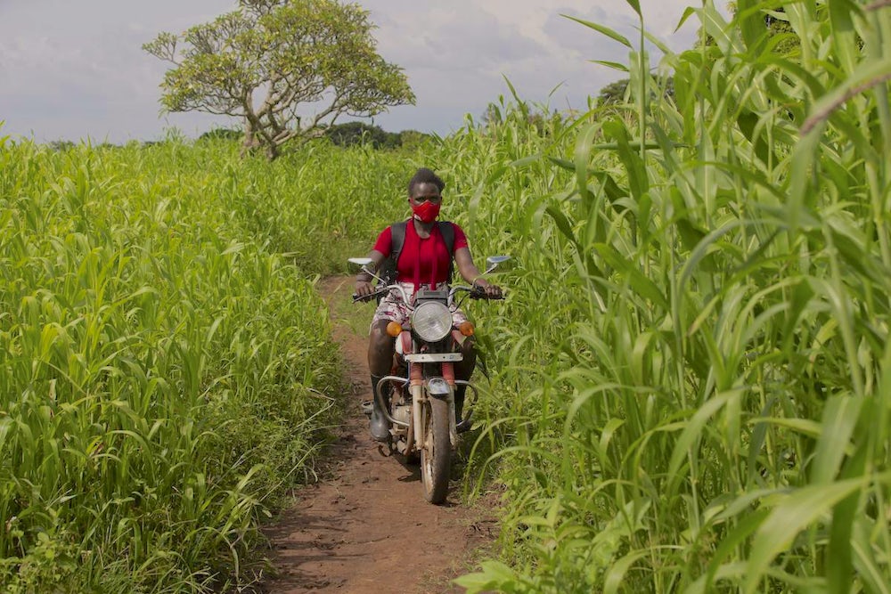 Amongi Leah travelling to farmers locations on her motorbike to deliver training.