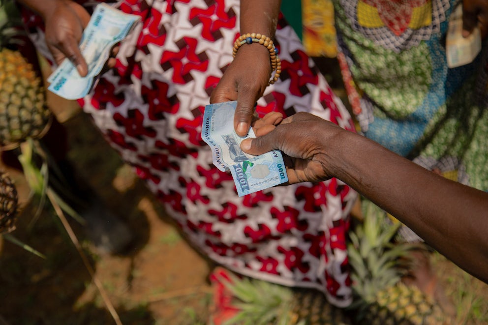 A close up shot shows two hands exchanging bills.