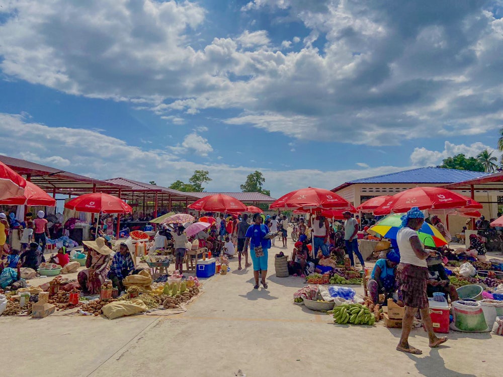 Numerous vendors sell their goods at a market in Haiti on a sunny day.